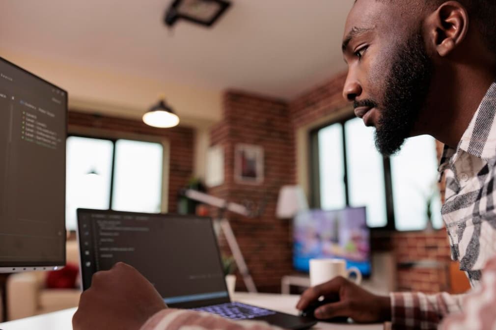 Man coding on a laptop in a home office setting